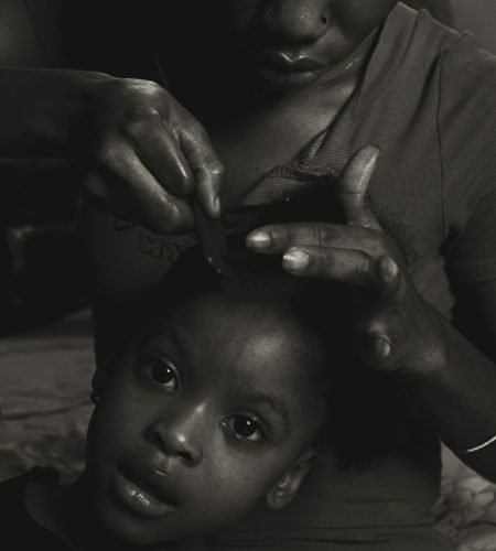 A touching black and white portrait of a mother combing her daughter's hair.